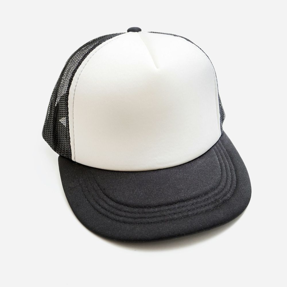 White and black trucker cap with a foam front and mesh back on a light grey background