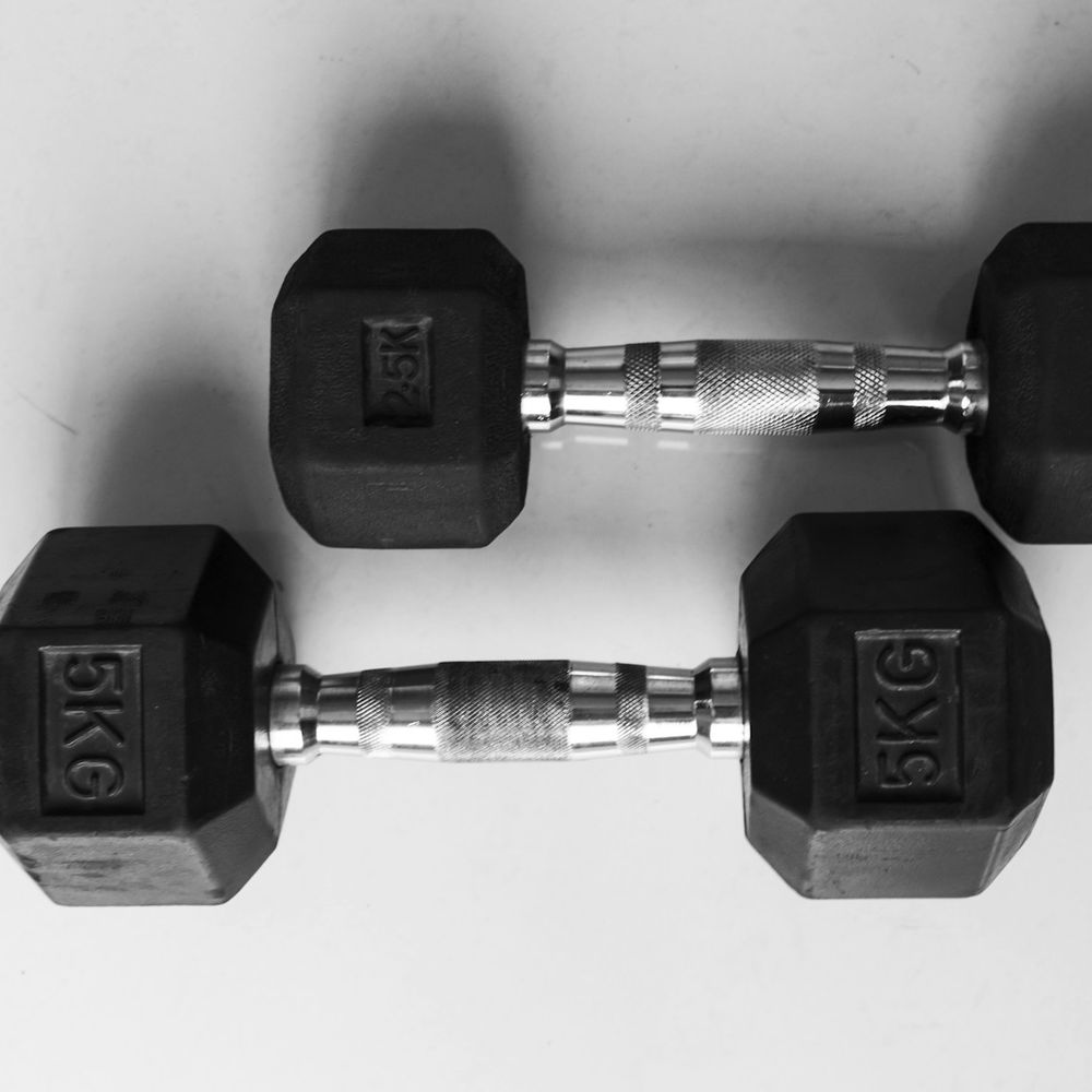 Pair of black hex dumbbells with chrome handles, each head marked 5 kg, on a white surface