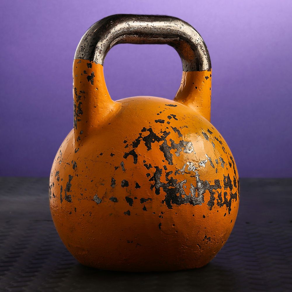 Orange painted kettlebell with a steel handle against a purple backdrop