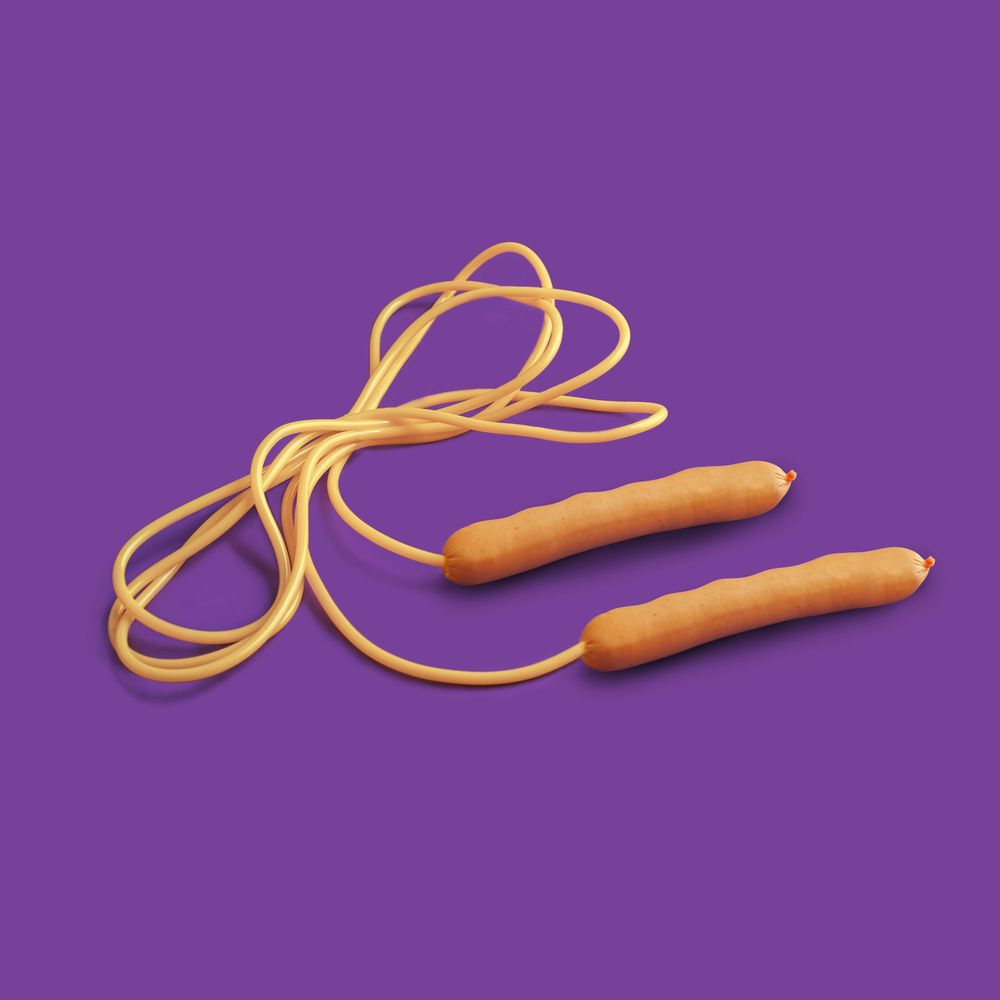 Yellow-orange skipping rope with orange handles coiled on a purple background